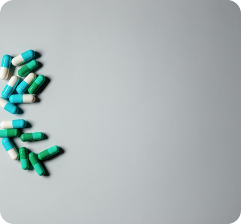 Blue and green capsules laid out on a grey surface.