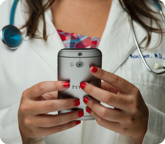 A doctor in a white coat holding a smartphone.
