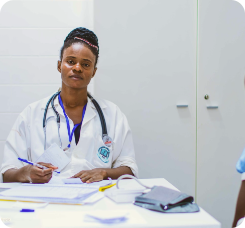 A doctor seated at a consulting-room desk taking notes.